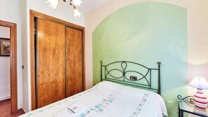 A bedroom with a bed, a wooden wardrobe, and a green wall.