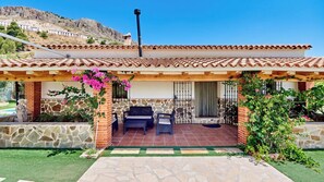 A house with a patio, stone walls, and a view of a hill.