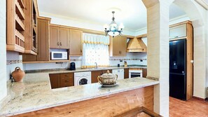 A kitchen with wooden cabinets, a microwave, a sink, and a refrigerator.