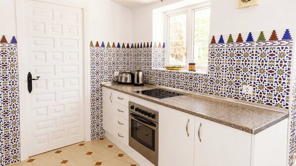 A kitchen with a white door, a window, and patterned tile backsplash.