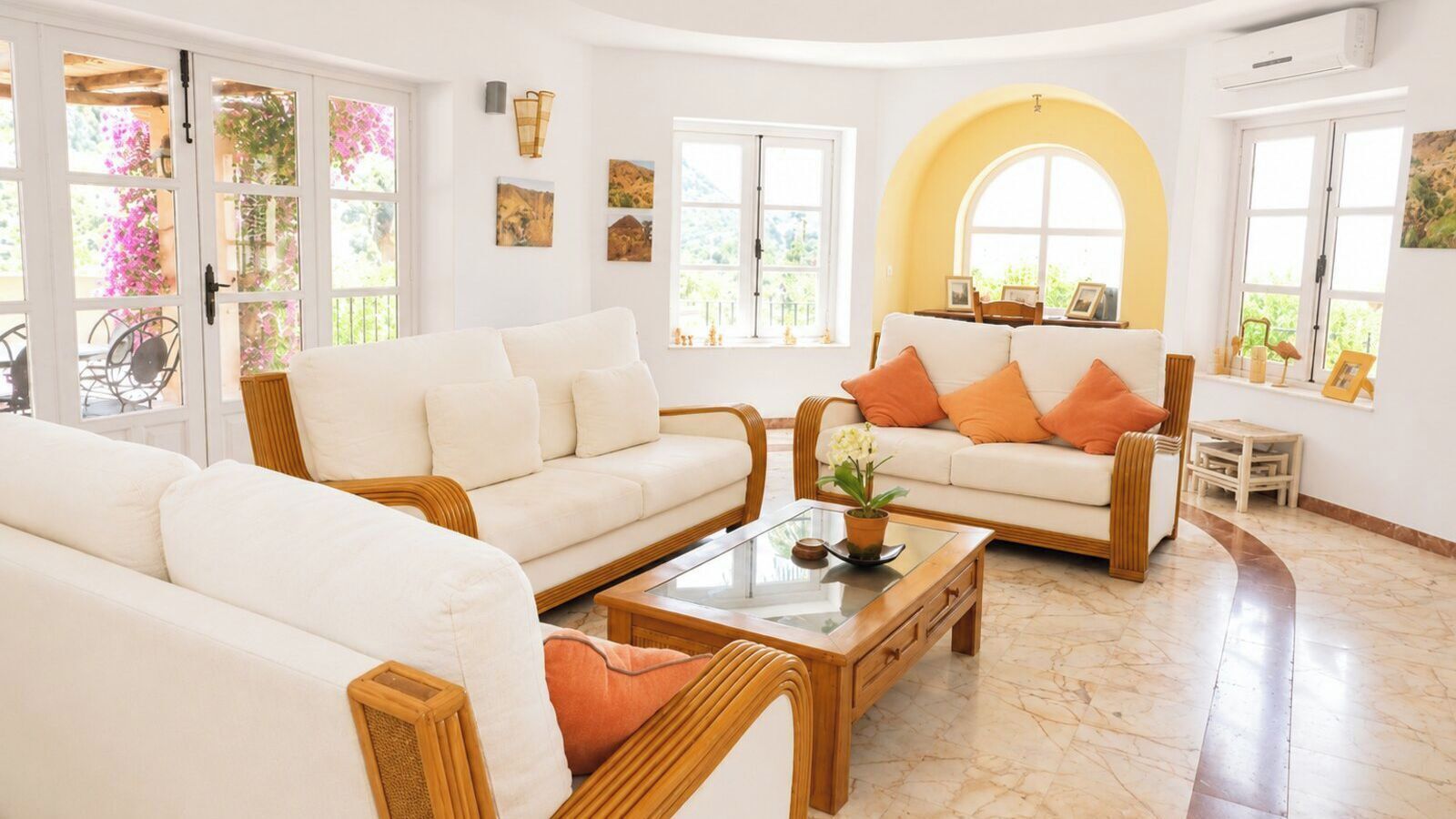 Un salón espacioso con dos sofás blancos, una mesa de centro de madera y un suelo curvado.