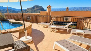 A rooftop pool area with lounge chairs and a hot tub, surrounded by a tiled deck and a view of distant mountains. - Villa Los Arcos Turre by Ruralidays (Almería)