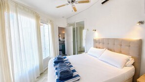 A hotel room with a large bed, a ceiling fan, and a view of the bathroom through a glass door. - Villa Los Arcos Turre by Ruralidays (Almería)