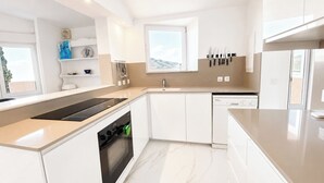 A modern kitchen with white cabinets, a built-in oven, a dishwasher, and a window with a view of the mountains. - Villa Los Arcos Turre by Ruralidays (Almería)