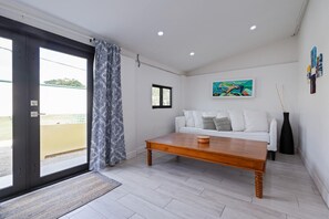 A modern living room with a white sofa, a wooden coffee table, and a large window with a view.