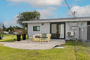 A single-story building with a covered patio area, outdoor seating, and a fenced yard.