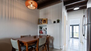 Een eethoek met een houten tafel en stoelen, een boekenkast en een hanglamp.