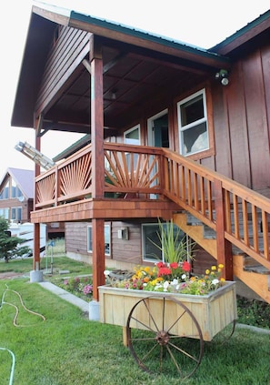 Une maison en bois dotée d’un porche couvert et d’un escalier en bois menant à une terrasse.