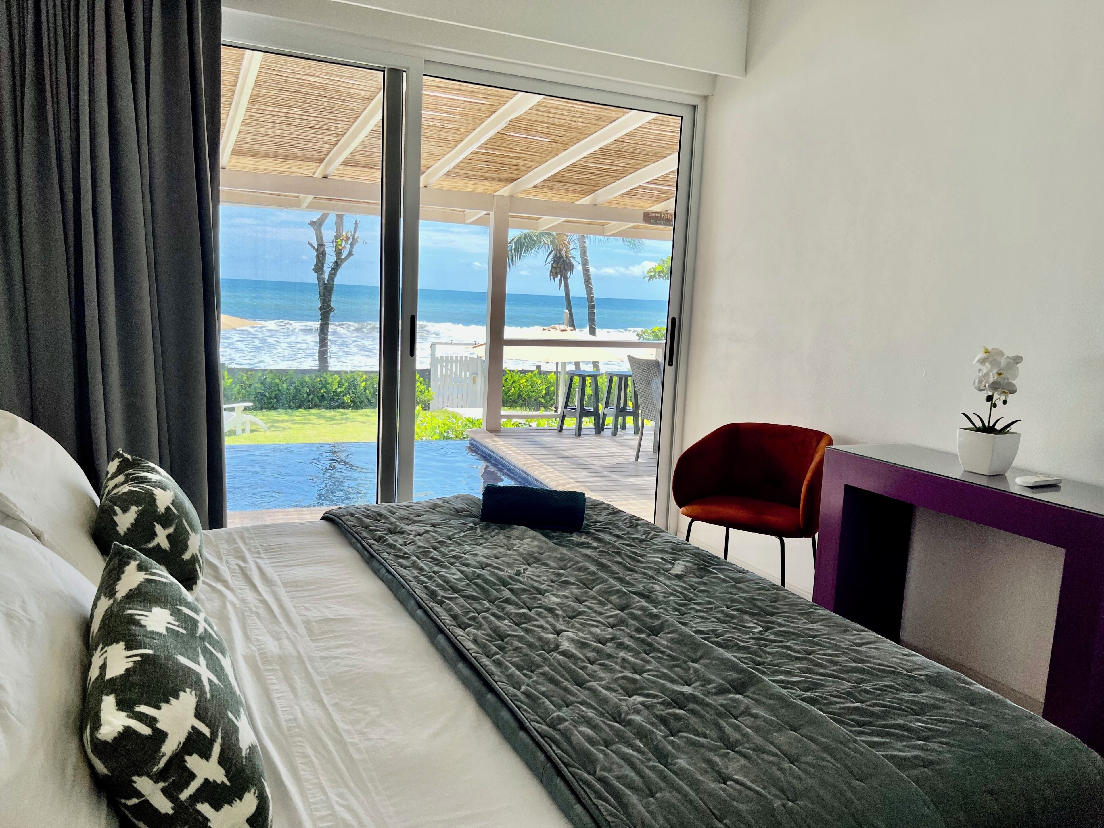 A hotel room with a bed, a desk, and a view of the ocean.