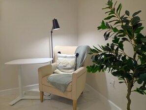 A corner room with a chair, a small table, a floor lamp, and a potted plant. - Family Nest Romantic Stay-Memories (Bradenton)