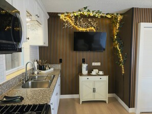 A kitchen with a built-in microwave, a coffee maker, and a flat-screen TV mounted on the wall. - Family Nest Romantic Stay-Memories (Bradenton)