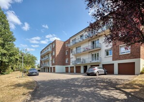 Ein mehrstöckiges Wohngebäude mit Backsteinfassade, Balkonen und einem Parkplatz mit Autos.