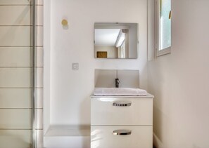Ein Badezimmer mit einem weißen Waschbecken, einem Spiegel darüber und einem Handtuch am Waschbecken.