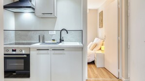 A modern kitchen with a built-in oven, a stove, a sink, and a black range hood. - Le Devillois - 4 chambres, balcon et garage près de Rouen (Déville-lès-Rouen)