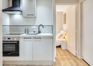 Eine moderne Küche mit Backofen, Herd, Spüle und einer schwarzen Dunstabzugshaube.