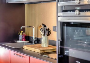 A modern kitchen with a stainless steel range hood, a wooden cutting board, and a utensil holder on the counter. - Valeria - Souplex élégant avec parking proche gare Rouen (Rouen)