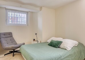 A bedroom with a bed, a chair, a window, and a bedside table. - Valeria - Souplex élégant avec parking proche gare Rouen (Rouen)
