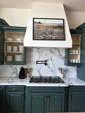 A kitchen with a gas stove, marble backsplash, and green cabinets. - New- Apache Junction, Amazing View, Hiking, Golf (Apache Junction)