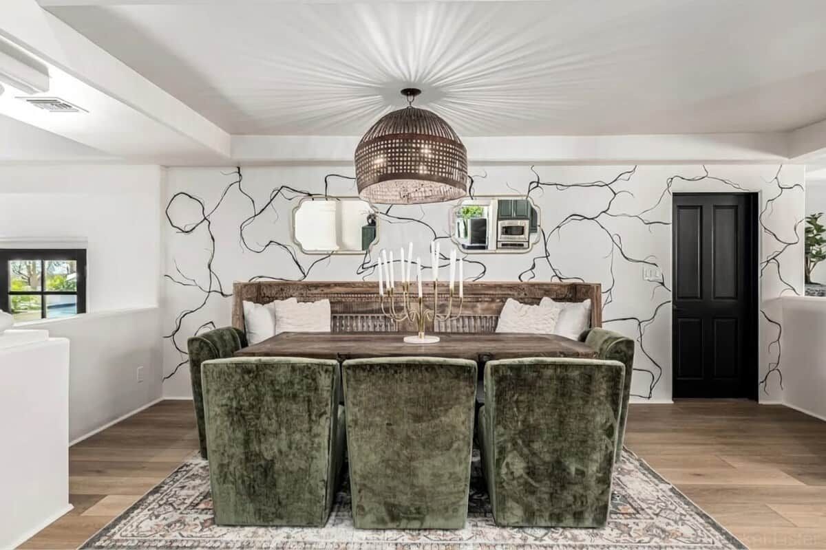 A dining area with a table set for four, a chandelier, and a wall with a crack-like design.