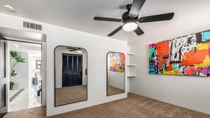 A room with a ceiling fan, two wall-mounted mirrors, and a colorful abstract painting. - Desert Estate at the Base of the Superstition Mountains (Apache Junction)