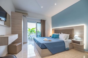 Habitación de hotel con cama, mesita de noche, lámpara y vistas al exterior.