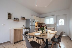 A compact kitchen with a built-in washing machine, a refrigerator, and a dining area with a table set for two.