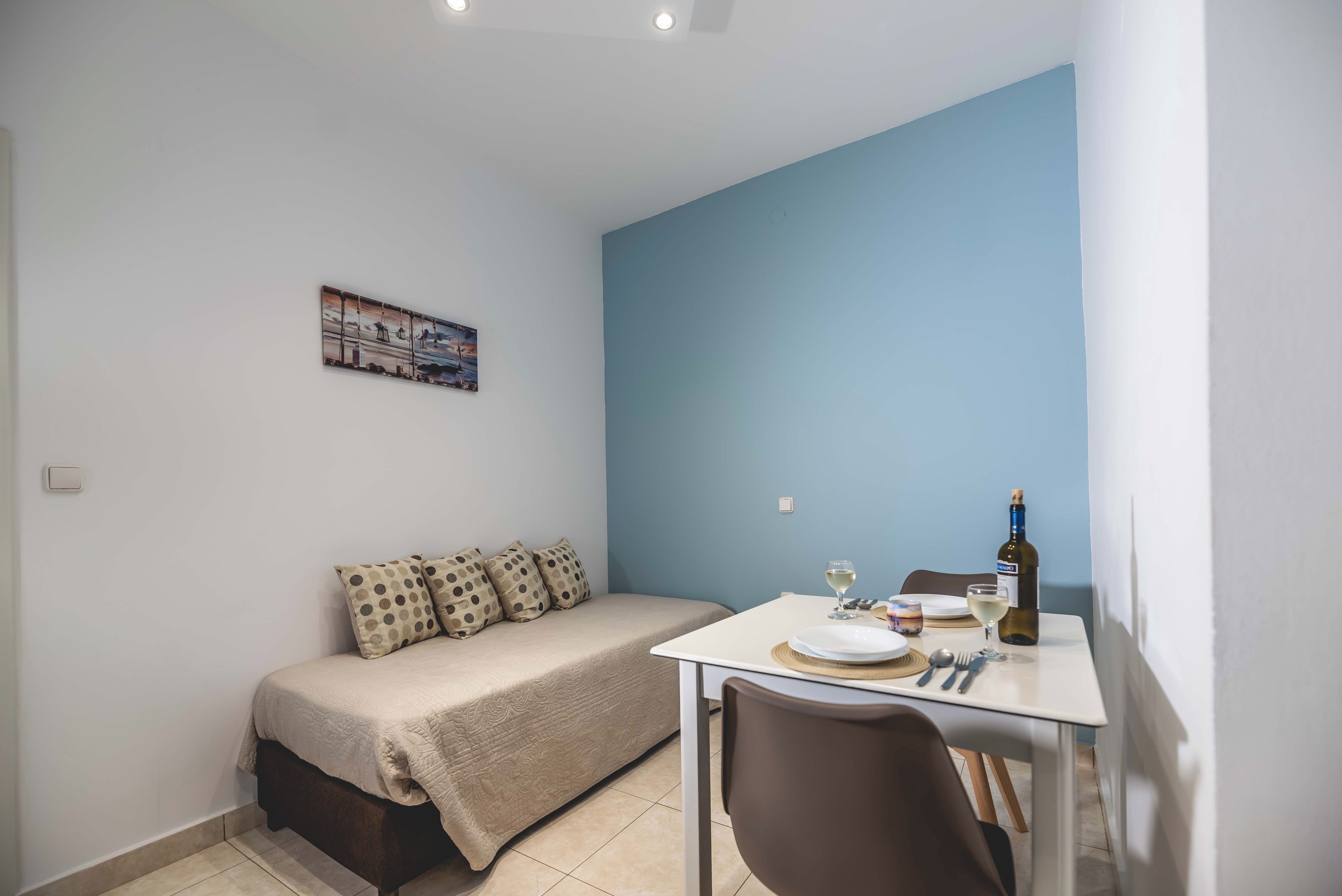 A small, neatly arranged room with a bed, a dining table, and a chair.