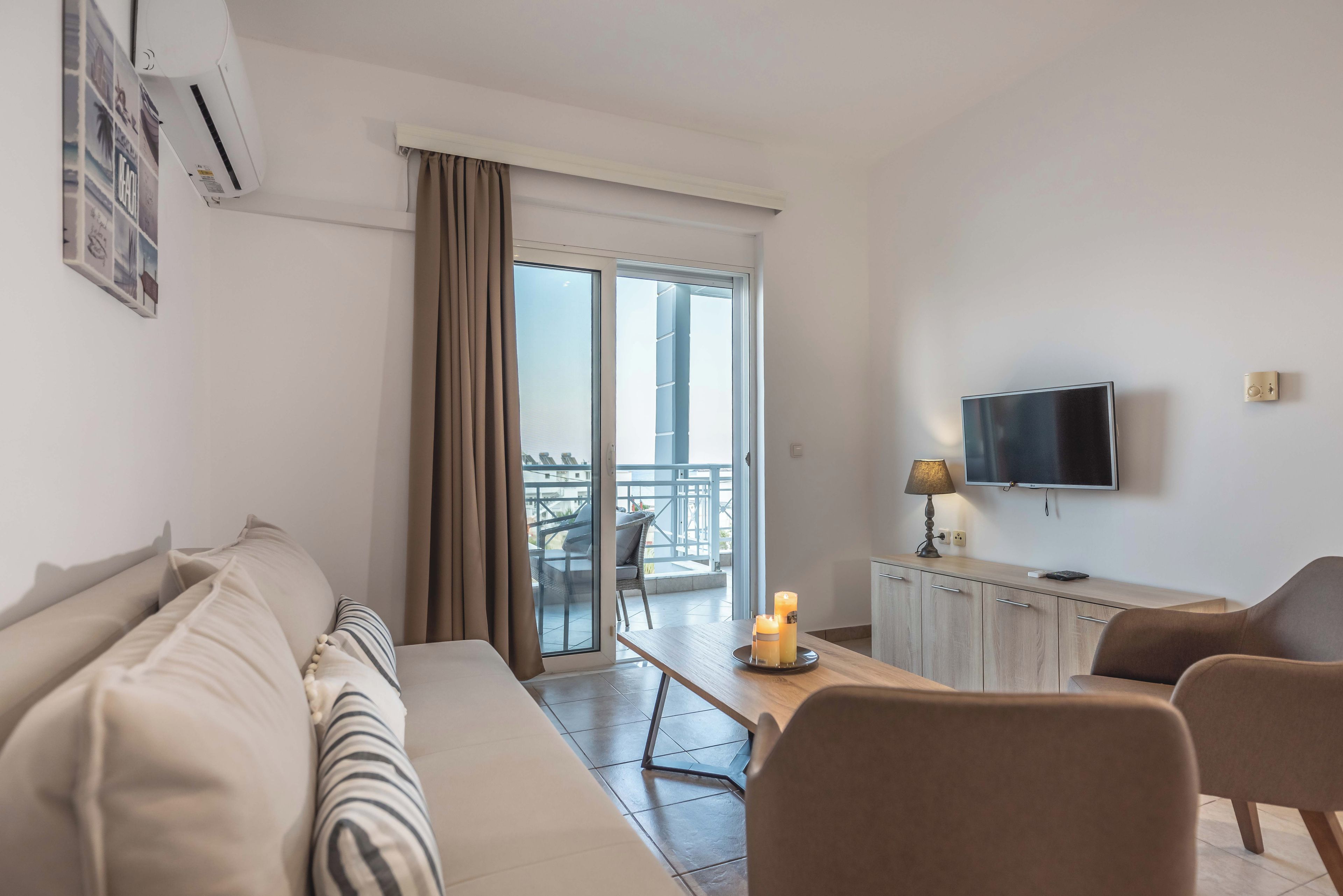 Sala de estar moderna com sofá, televisão, mesa com velas e varanda com vista.