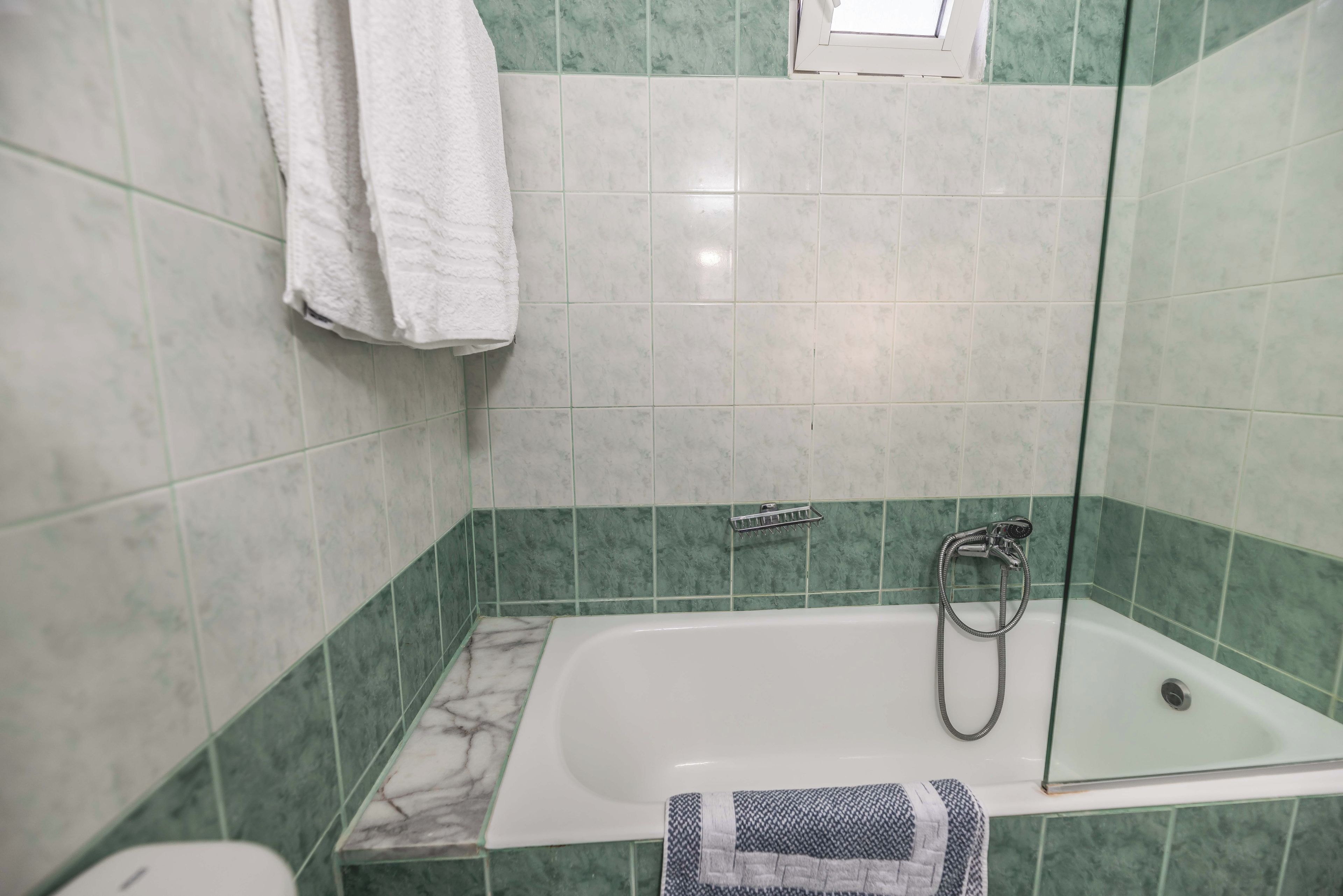 Un baño con bañera, ducha y zona de ducha con mampara de vidrio.