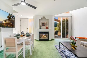 Ein modernes Wohnzimmer mit Kamin, Essbereich und einer Couch.
