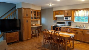 Una cocina con armarios de madera, una mesa de comedor con sillas, un microondas y una estufa.