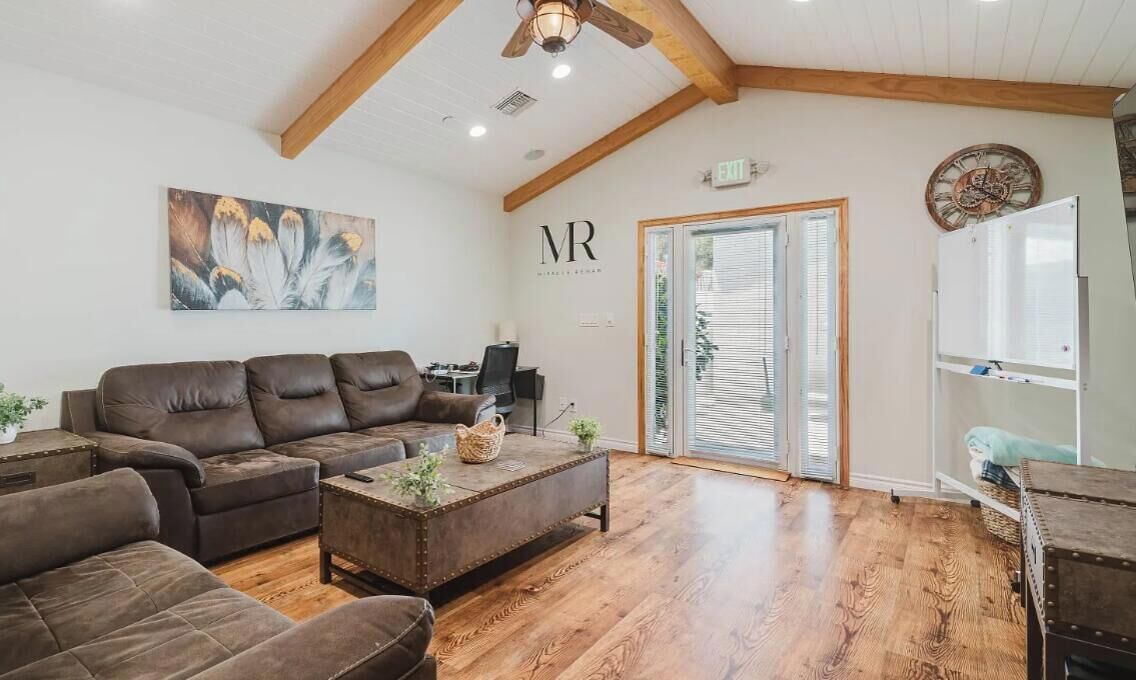 A spacious living room with a brown leather sofa, a coffee table, and a wooden ceiling.