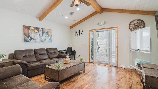 A spacious living room with a brown leather sofa, a coffee table, and a wooden ceiling. - 3-bedroom house in charming Burbank with cool AC (Burbank)