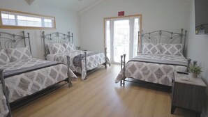 A room with two beds, a wooden floor, a small bedside table with a plant, and a door with an exit sign. - 3-bedroom house in charming Burbank with cool AC (Burbank)