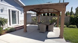 A covered patio with a table and chairs, a house in the background, and a well-maintained garden. - 3-bedroom house in charming Burbank with cool AC (Burbank)