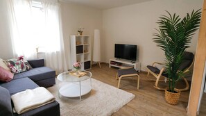Een moderne woonkamer met een bank, salontafel, televisie en een boekenkast.