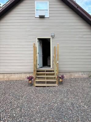 A wooden building with a door, a window, and a small porch with steps.