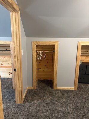 A room with a wooden closet, a hanging rack, and a carpeted floor. - Serene 3-bedroom house with AC just outside of Ladysmith. Pet-Friendly. (Ladysmith)