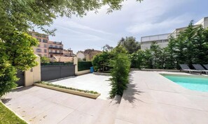Et beboelsesområde udendørs med en swimmingpool, en belagt terrasse og en lille have.