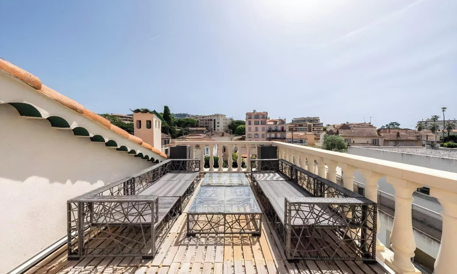 A rooftop terrace with a view of the cityscape, featuring a railing and a wooden deck.
