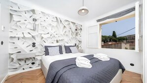 Un dormitorio con una cama, una ventana y una pared con diseño de hojas.