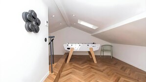 Una habitación con una mesa de fútbol de mesa, una silla y un par de mancuernas en la pared.
