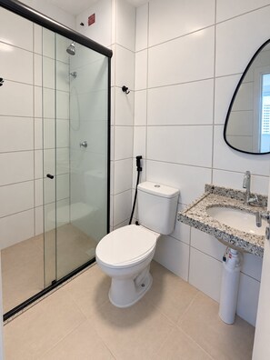 Ein modernes Badezimmer mit einer gläsernen Duschkabine, einer weißen Toilette und einem Waschbecken mit Marmorplatte.