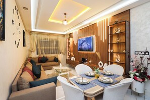 A modern living room with a sofa, TV, dining table, and decorative shelves. - Tanger Élégance Smart Stay WIFI & Netflix (Tanger)