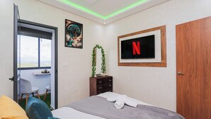 Ein Schlafzimmer mit einem Bett, einem an der Wand befestigten Fernseher, einer Tür und einem Fenster mit Blick.