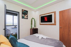 A bedroom with a bed, a TV mounted on the wall, a door, and a window with a view. - Tanger Élégance Smart Stay WIFI & Netflix (Tanger)
