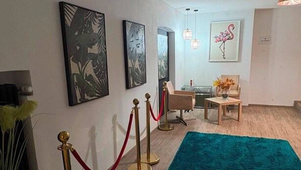 A hotel lobby with a teal carpet, artwork on the walls, a reception desk, and a seating area. - Eibisch Apartments (Passau)
