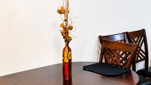 Ein Esstisch mit Stühlen, eine Vase mit Trockenblumen und ein dekoratives Wandbild.