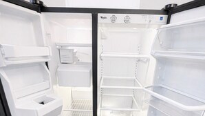 Ein offener Kühlschrank mit mehreren Ablagen und einem Wasserspender.