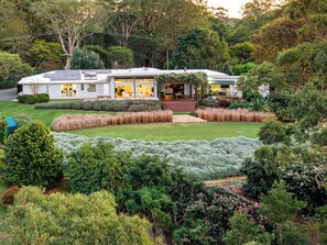 A modern house with a large garden, a covered outdoor seating area, and a well-maintained lawn.
